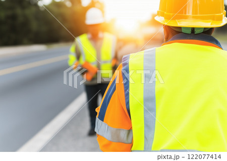 Safety-focused Construction Workers in Vests Collaborating on a Project at Sunrise 122077414