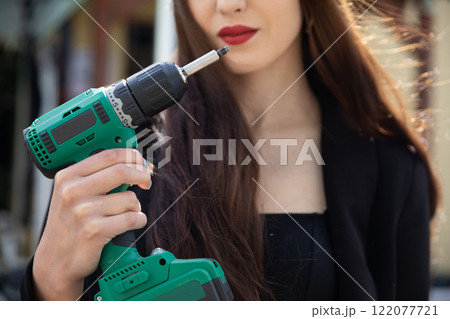 A Confident Woman Holding a Power Drill Demonstrates Strength and Skill in Construction 122077721