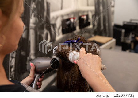 Experience the art of professional hair styling with a blow dryer and brush technique Experience the art of professional hair styling with a blow dryer and brush technique 122077735
