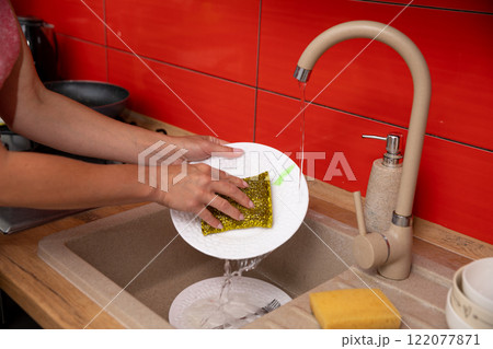 Washing Dishes in a Modern Kitchen that Features Attractive Red Accents Throughout 122077871