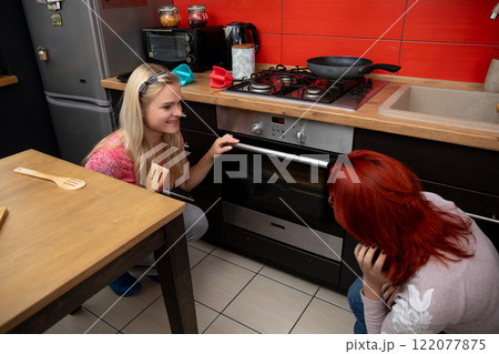 Two Women Joyfully Cooking Together in a Bright and Modern Kitchen Setting, Full of Light and Color 122077875