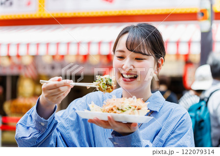 大阪道頓堀で名物のたこ焼きを食べる女性 122079314