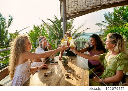 Group of diverse women toasting drinks at sunny restaurant table. Smiling friends celebrate special event. Cheerful brunch or bachelorette. Happy moments, positive vibes. Group of diverse women toasting drinks at sunny restaurant table. Smiling friends celebrate special event. Cheerful brunch or bachelorette. Happy moments, positive vibes. 122079373