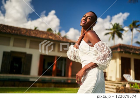 Ambiguous gender fluid person in white wedding dress in villa garden. LGBTQ wedding theme with blue sky, palms. Elegant style, inclusive celebration. Perfect for diverse bridal. Ambiguous gender fluid person in white wedding dress in villa garden. LGBTQ wedding theme with blue sky, palms. Elegant style, inclusive celebration. Perfect for diverse bridal. 122079374