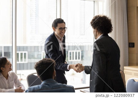 Business partners starting cooperation shaking hands in boardroom 122080937
