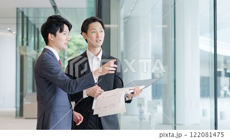 図面を持ち打ち合わせをするビジネスマン 122081475