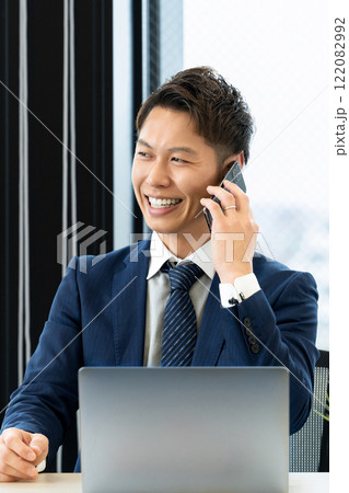 スマホで通話をする笑顔の男性ビジネスマン スマホで通話をする笑顔の男性ビジネスマン 122082992