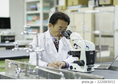 顕微鏡を除いてメモを取る医師　撮影協力：学校法人電波学園 東京電子專門学校 122083011