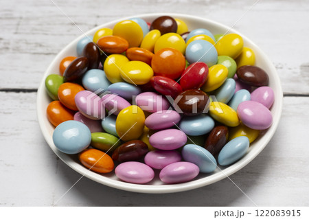 丸形の小皿に入ったカラフルな粒チョコレート 122083915