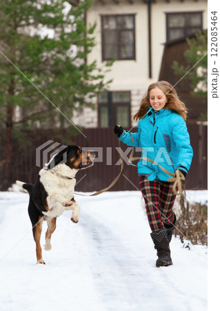 Smiling woman running with her sennenhund dog on snowy path, enjoying a winter walk. Capturing friendship, activity, and outdoor fun in cold and cheerful environment. Smiling woman running with her sennenhund dog on snowy path, enjoying a winter walk. Capturing friendship, activity, and outdoor fun in cold and cheerful environment. 122085464