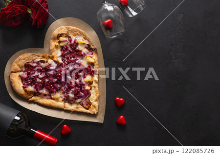 Food for Valentine's Day. Heart shaped sweet pizza with pineapple on black background. View from above. Copy space. Romantic dinner with red wine and gift. 122085726