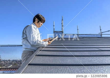 戸建て家屋の屋根修繕工事進行状況を確認する男性 122085806