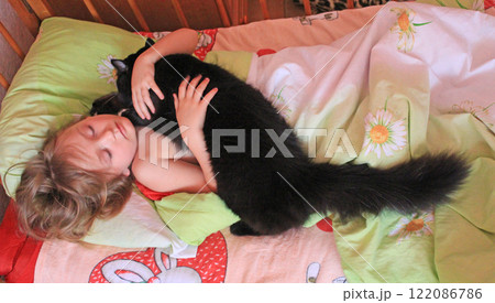 Little girl laying in bed together with her cat. Together with your pet Little girl laying in bed together with her cat. Together with your pet 122086786