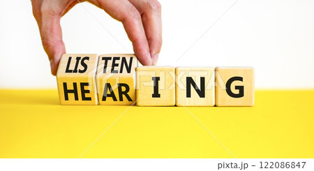 Listening or hearing symbol. Businessman turns wooden cubes and changes a concept word Listening to Hearing. Beautiful white background. Copy space. Business educational listening or hearing concept. Listening or hearing symbol. Businessman turns wooden cubes and changes a concept word Listening to Hearing. Beautiful white background. Copy space. Business educational listening or hearing concept. 122086847