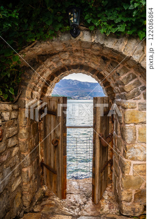 Old street in old town of Budva without people in winter time with small gate in the end to sea coast, Montenegro.  122086864
