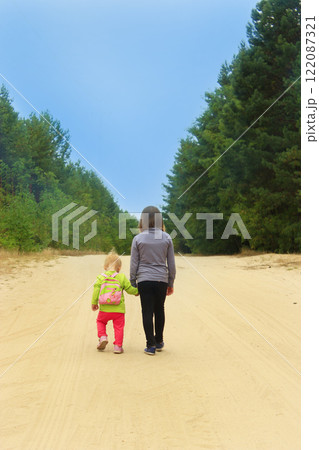Little tourists go on road. Girls travellers walk on the forest path Little tourists go on road. Girls travellers walk on the forest path 122087321