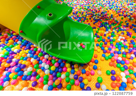 A fun green slide leading into a vibrant ball pit filled with colorful plastic balls. 122087759
