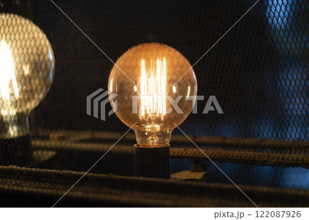 Vintage incandescent Edison light bulb glowing in the dark. Vintage incandescent Edison light bulb glowing in the dark. 122087926