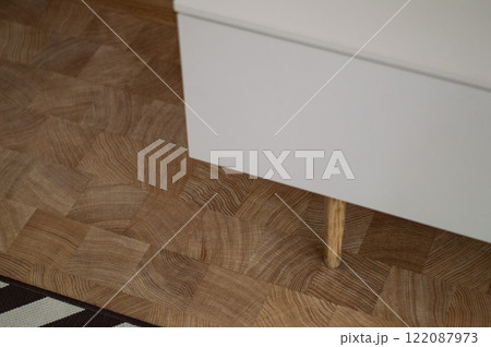 A white wooden dresser on legs on a wooden floor background A white wooden dresser on legs on a wooden floor background 122087973