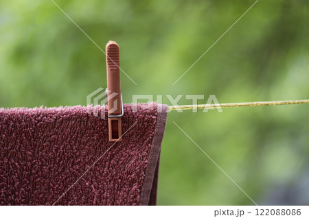 A pink towel with a pink clothespin is drying outside A pink towel with a pink clothespin is drying outside 122088086