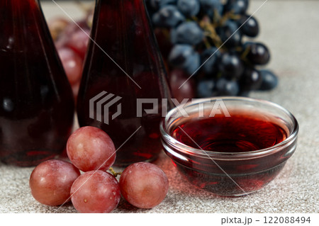 Red wine vinegar in glass vinegar bowls among grapes 122088494