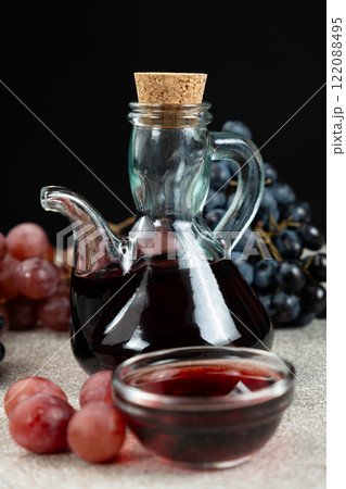 Red wine vinegar in glass vinegar bowls among grapes 122088495
