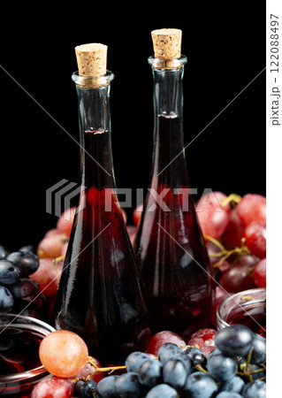 Red wine vinegar in glass vinegar bowls among grapes 122088497