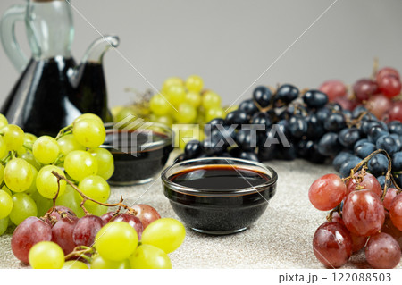 Balsamic vinegar poured into a glass sauce dish among the grapes 122088503