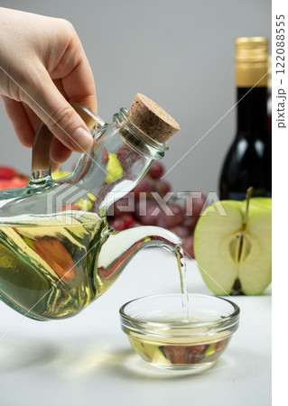 Vinegar pouring from vinegar bowl into glass sauce dish Vinegar pouring from vinegar bowl into glass sauce dish 122088555
