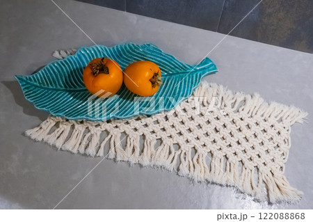 persimmons displayed in bowl on a macrame decor woven textile in table of kitchen persimmons displayed in bowl on a macrame decor woven textile in table of kitchen 122088868