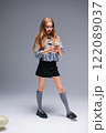 A Trendy Young Girl Dressed in Stylish and Chic Attire, Holding a Smartphone in a Creative Manner 122089037