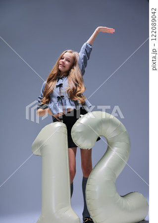A Cheerful and Joyful Model Posing with a Colorful Inflatable Number 12 in a Studio Setting A Cheerful and Joyful Model Posing with a Colorful Inflatable Number 12 in a Studio Setting 122089042