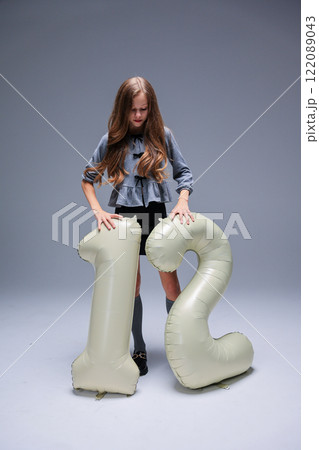 A young girl with an inflatable item sized 12 inches poses during a vibrant fashion photo shoot 122089043
