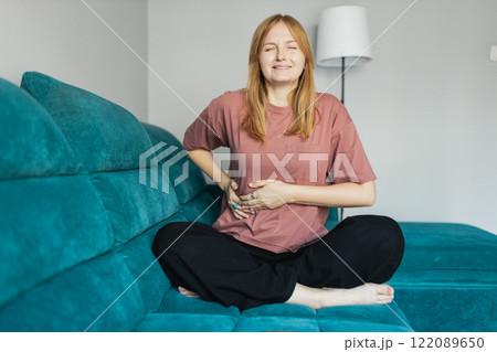 30s woman having a stomachache. Young woman suffering from abdominal pain. Young blonde girl in bad thoughts feeling lonely indoors and touching her stomach. Full body 30s woman having a stomachache. Young woman suffering from abdominal pain. Young blonde girl in bad thoughts feeling lonely indoors and touching her stomach. Full body 122089650