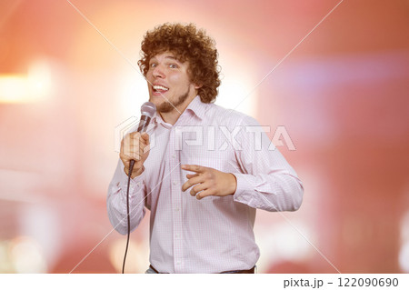 Happy excited young man with curly hair singing in microphone. Abstract glowing background. Happy excited young man with curly hair singing in microphone. Abstract glowing background. 122090690