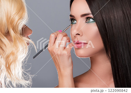Makeup artist applying eyeshadow on model eyes Makeup artist applying eyeshadow on model eyes 122090842