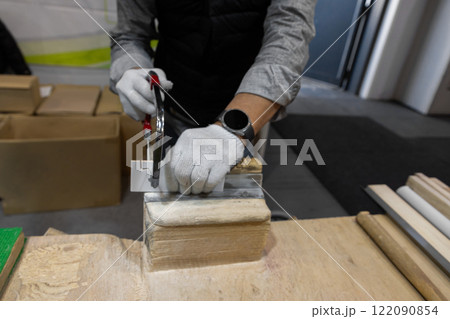 male hands in work gloves sawing wooden blank with thin hand saw 122090854