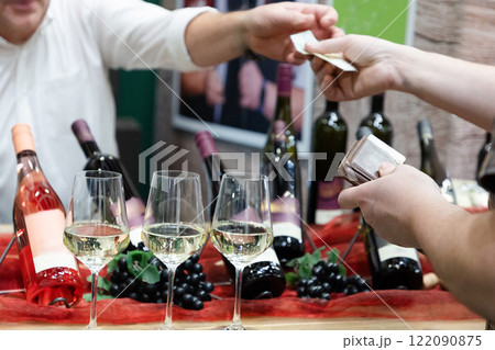 buyer's hand taking a bottle of wine from stand 122090875