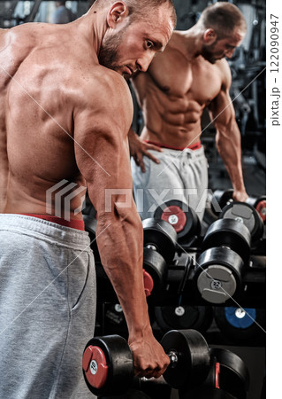 Young and muscular man with a dumbbell in the gym 122090947