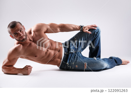 Handsome muscular man wearing jeans posing in studio Handsome muscular man wearing jeans posing in studio 122091263