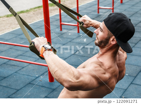 Man during workout with suspension straps on street 122091271