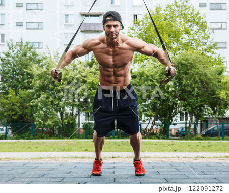 Man during workout with suspension straps on street 122091272