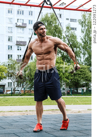 Man during workout with suspension straps on street 122091273