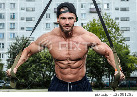 Man during workout with suspension straps on street 122091283