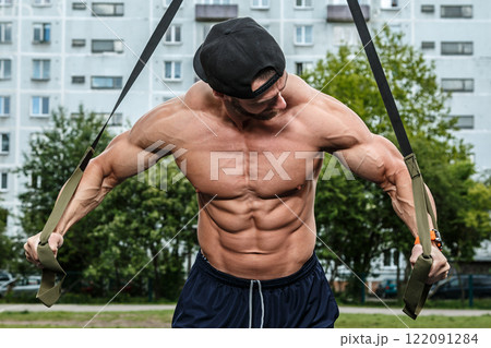 Man during workout with suspension straps on street 122091284