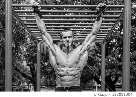 Muscular man doing pull-ups on horizontal bar Muscular man doing pull-ups on horizontal bar 122091304