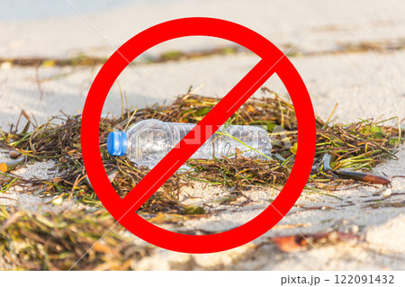 Plastic bottle on sandy beach with a red prohibition sign symbolizing environmental pollution and waste prevention 122091432