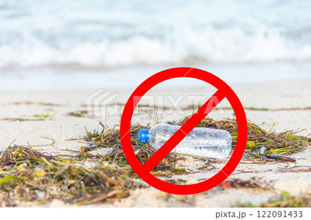 Plastic bottle on sandy beach with a red prohibition sign symbolizing environmental pollution and waste prevention 122091433