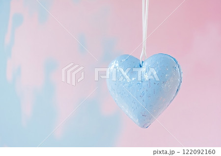 Light blue heart hanging on white string on pink and light blue background 122092160