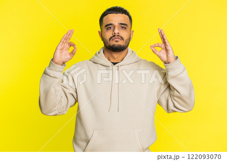 Indian man meditating breathes deeply with mudra yoga gesture, eyes closed, taking a break, relax Indian man meditating breathes deeply with mudra yoga gesture, eyes closed, taking a break, relax 122093070